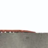 A red Food Production Mat with a wavy texture lies unevenly on the edge of a grey concrete surface against a plain white background.