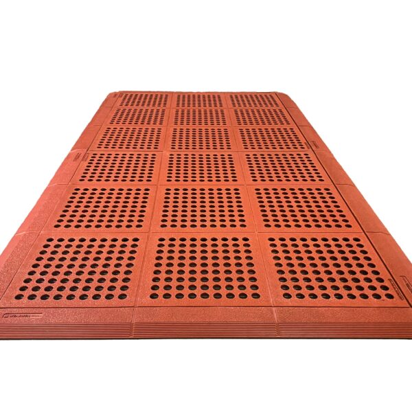 The Interlocking Catering Mat is a large rectangular orange mat with a grid pattern of raised dots, designed to assist visually impaired pedestrians.