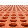 Close-up of the Interlocking Catering Mat, featuring an orange rubber design with a textured surface and evenly spaced round holes, photographed from a low angle.