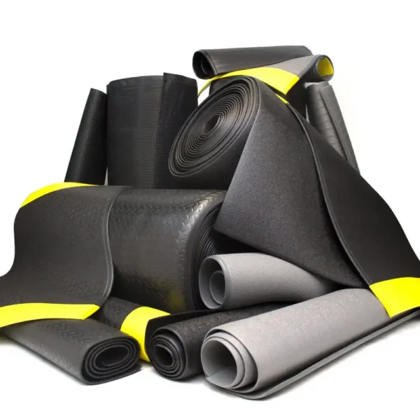 A pile of rolled-up Standard Anti-Fatigue Mats in black and grey, some secured with yellow bands, arranged against a plain white background.