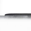 A close-up of the Standard Anti-Fatigue Mat’s textured black surface, partially visible behind a rough, grey, stone-like layer against a plain white background.