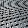 Close-up of the Anti-Slip Mat, showing its textured rubber surface with a repeating hexagonal and circular hole pattern for enhanced grip and drainage, photographed at an angle.