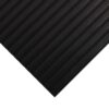 A close-up of the Interlocking Bubble Top Stable Mat, black with diagonal grooved lines, is shown on a white background with a pointed corner facing the bottom right-hand side.