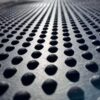 Close-up of the Raised Top Stable Mat’s metal surface, featuring evenly spaced raised circular bumps in rows. Reflected light emphasises the textured, repeating pattern and sense of depth.