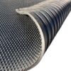 A close-up of the Raised Top Stable Mat, a black rubber mat featuring a raised dot pattern on one side and grooves on the other, partially rolled to display both textured surfaces.