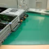 A partially disassembled server rests on Conductive Rubber Bench Matting, exposing its metal casing and components, with server rails placed alongside on the green mat.