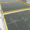 Open Top Grating panels with square openings and yellow-bordered edges create a clean, industrial walkway. A metal safety railing runs along the right side for protection.
