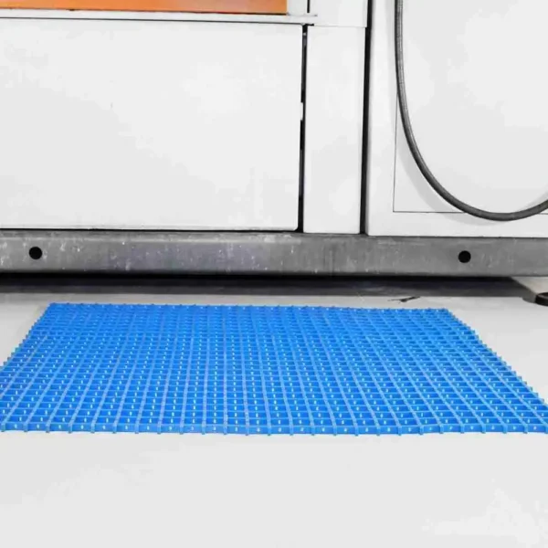 A Standard Cross-Ribbed Mat in blue with a grid pattern is placed on the floor in front of a washing machine and cupboards.