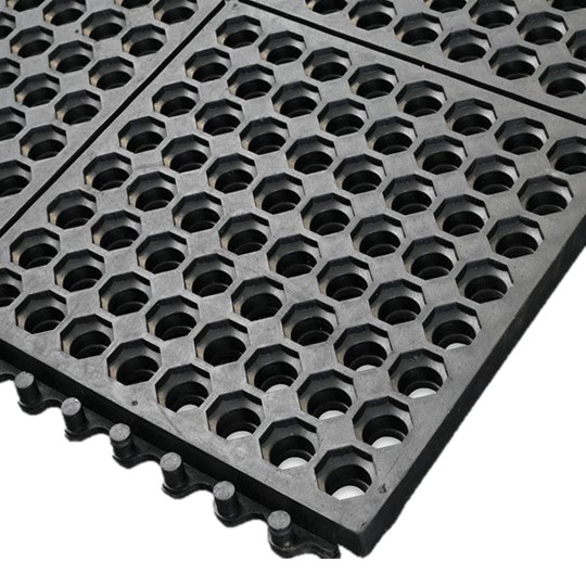A close-up view of the Interlocking Anti-Fatigue Mat, featuring black rubber construction with a honeycomb pattern of hexagonal holes and interlocking edges.