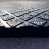Close-up image of the Diamond Top Stable Mat’s textured, dark surface featuring a grid pattern with raised, bumpy squares, photographed at an angle to highlight its glistening, light-reflective finish.
