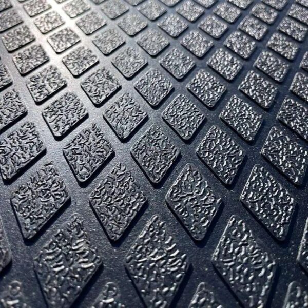 Close-up of the Diamond Top Stable Mat, showcasing its textured rubber surface with a repeating pattern of raised diamond shapes arranged in neat rows under bright lighting.