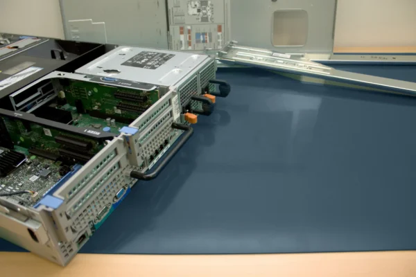 An open computer server sits on an ESD Anti-Static Double Layer Sheet, its metal cover removed to reveal internal circuit boards, data ports, and wiring, ensuring static protection during dismantling.