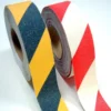 Two upright rolls of GRP Grit Tape—one yellow/black striped, the other red/white striped—are shown against a plain white background.
