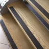 Wooden stairs with GRP Grit Tape black non-slip strips affixed to each step for added safety. The photo shows the steps from above at an angle, highlighting the textured GRP Grit Tape and wood grain.