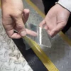 A person peels a strip of Anti-Slip Comfortable Tape from a chequered metal surface, next to a black strip and a yellow raised marker.