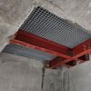 A ceiling view of a construction site shows red steel Angle Profiles supporting a metal grid panel, surrounded by unfinished concrete surfaces.