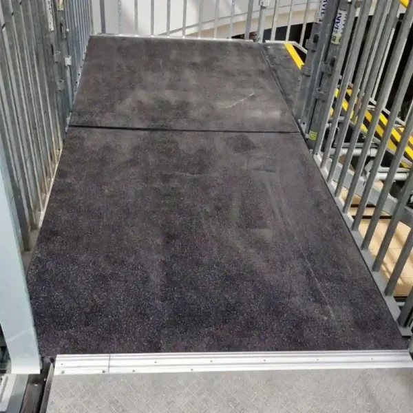 An Anti-Slip Flat Sheet with a dark, textured finish forms a wheelchair ramp bordered by metal railings on both sides, providing secure access to a higher level.