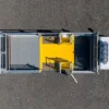 Aerial view of a rectangular animal handling facility with metal gates and an Anti-Slip Flat Sheet in the centre, featuring two open side doors on a grey asphalt surface.