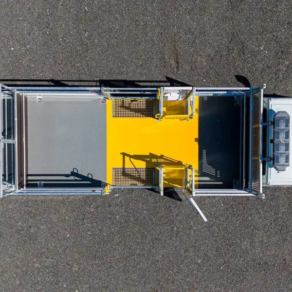 Aerial view of a rectangular animal handling facility with metal gates and an Anti-Slip Flat Sheet in the centre, featuring two open side doors on a grey asphalt surface.