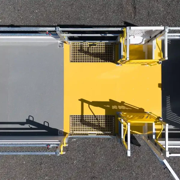 Aerial view of a yellow and grey metal industrial walkway featuring Anti-Slip Flat Sheet panels with grated and solid flooring, safety railings, gates, and set on a tarmac surface.