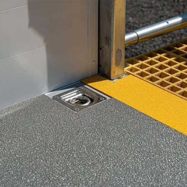 Close-up of Anti-Slip Flat Sheet in grey with a recessed metal tie-down anchor, yellow non-slip strip, and metal railing adjacent to grated flooring.