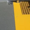 Close-up of an Anti-Slip Flat Sheet with a textured grey surface beside a yellow textured section, featuring a yellow grid mat inset and a metal fitting in the top left corner.
