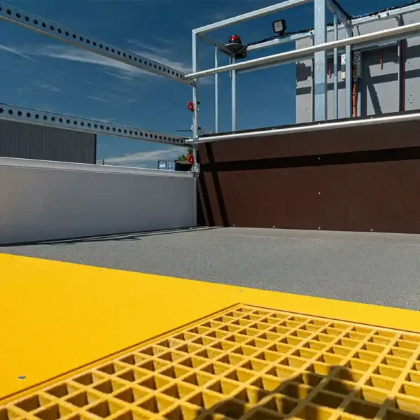 Close-up of an Anti-Slip Flat Sheet rooftop safety platform featuring a yellow gritted surface, grey flooring, and metal guardrails under a blue sky.