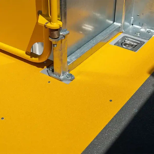 Close-up of a yellow Anti-Slip Flat Sheet and metal fittings in a vehicle, showing part of the door mechanism, pole, and base with bright colours and reflective surfaces.