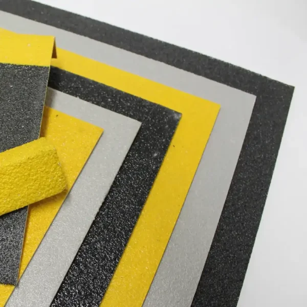 Black, yellow, and grey Anti-Slip Sheets are stacked in a fanned arrangement on a white background. The textured surfaces highlight their slip-resistant properties.
