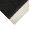 Close-up of an Anti-Slip Stair Tread showing a rough, textured black surface meeting a lighter, off-white strip at the corner, creating a sharp visual contrast.