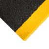 Close-up of the Anti-Slip Stair Tread showcasing its textured black surface and bright yellow edge. The image highlights the corner, thickness, and material detail against a white background.