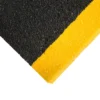 Close-up of the Anti-Slip Stair Tread’s textured surface, diagonally divided: black on the upper left and bright yellow on the lower right. The rough finish enhances grip for added stair safety.