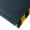 A close-up of the Foam Cushioned Industrial Mat, featuring black rubber with raised circular bumps and yellow-and-black caution stripes on the edges, commonly used in workplaces for safety and anti-fatigue support.