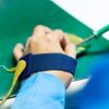 Someone wearing a blue Wristbands anti-static wrist strap, attached with a yellow wire, uses a soldering iron on an electronic circuit board placed on a green work surface.