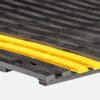 Close-up of the Self-Draining Safety Mat features a textured black rubber surface with raised, angled grooves and two bright yellow strips running parallel across it.