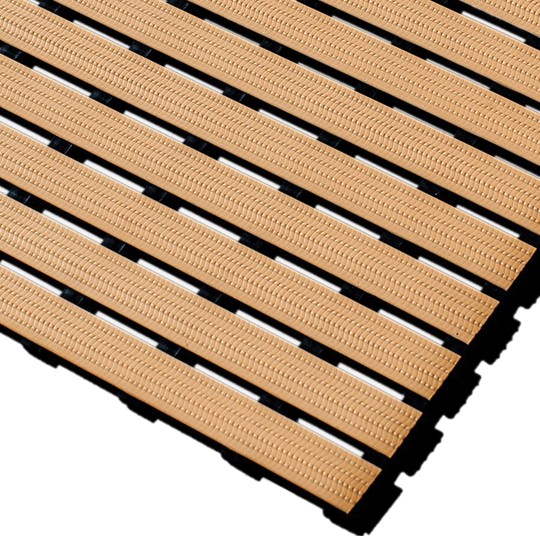 Close-up of Cross-Ribbed PVC Leisure Mat tiles in tan, featuring textured grooves and interlocking slats arranged diagonally on a white background. The gaps between the slats expose the black base structure beneath.