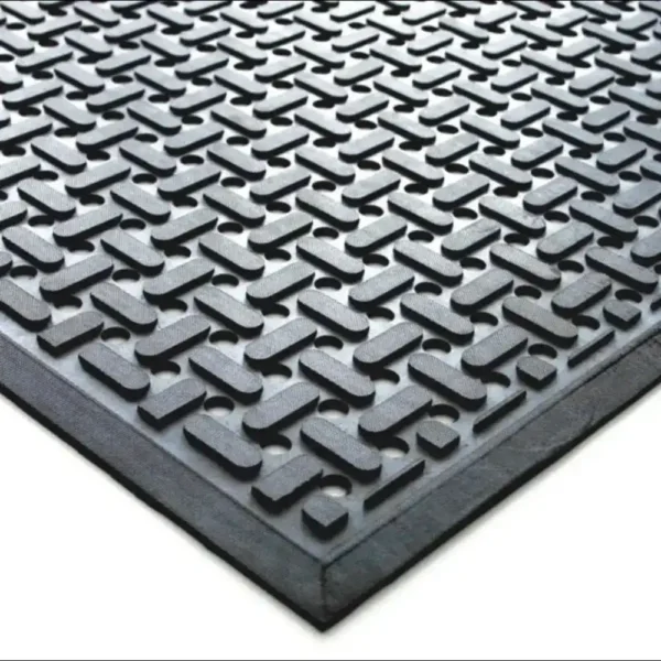 Close-up of the Nitrile Workplace Mat, a black rubber floor mat with a raised, repeating geometric pattern of interlocking curves, shown at an angle to highlight its texture and thickness.