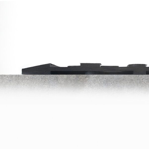 A close-up of the Nitrile Workplace Mat's rough, textured edge with a blurred, gear-like object resting on top against a plain white background.