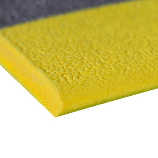 Close-up of the Standard Anti-Fatigue Mat in yellow, featuring a textured surface and bevelled edge, resting on a grey surface. The mat is constructed from durable foam material.