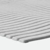 Close-up of a white Swimming Pool Mat with a textured foam surface featuring evenly spaced, parallel ridges and small speckles. The mat appears soft, flexible, and has a wave-like ridge pattern.