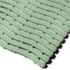 Close-up of Swimming Pool Mat interlocking green tiles featuring a wavy, slotted pattern for drainage. The modular design with overlapping edges is highlighted by the angled arrangement.