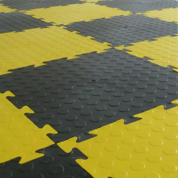 Close-up of Circular Stud Interlocking Tiles in a yellow and black chequerboard pattern, each tile featuring a raised circular stud texture for enhanced grip and traction.