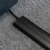 The PVC Cable Protector shields a lead on a grey carpeted floor, organising it and preventing tripping.