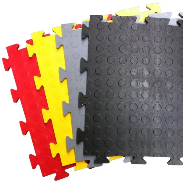 Four Circular Stud Interlocking Tiles in red, yellow, grey, and black are arranged fan-shaped. Each tile features a circular raised dot pattern and puzzle-like edges for easy connection.