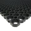 Close-up of the Grass Mat Roll (1m x 10m x 22mm), featuring a black rubber design with a grid of circular and square holes for a textured, non-slip surface. The mat is shown extending into the distance.