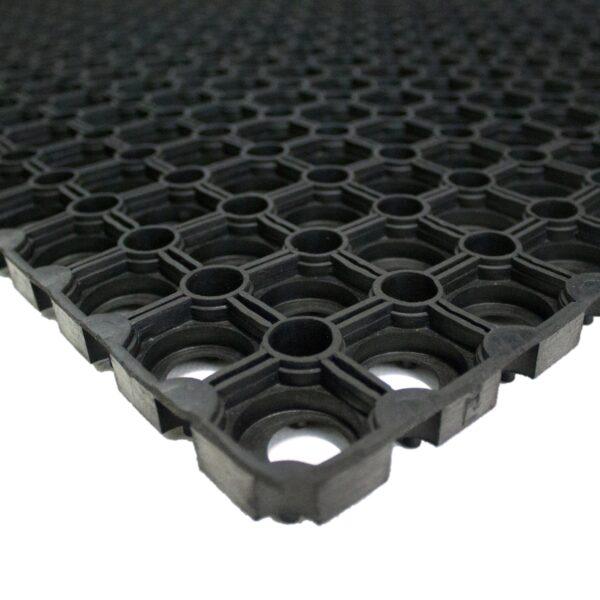 Close-up of the Grass Mat Roll (1m x 10m x 22mm), featuring a black rubber design with a grid of circular and square holes for a textured, non-slip surface. The mat is shown extending into the distance.