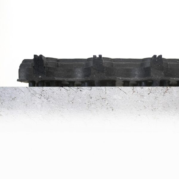 A Grass Mat Roll (1m x 10m x 22mm) in black with a textured finish rests on a rough, light grey concrete surface showing cracks and scratches, set against a white background.
