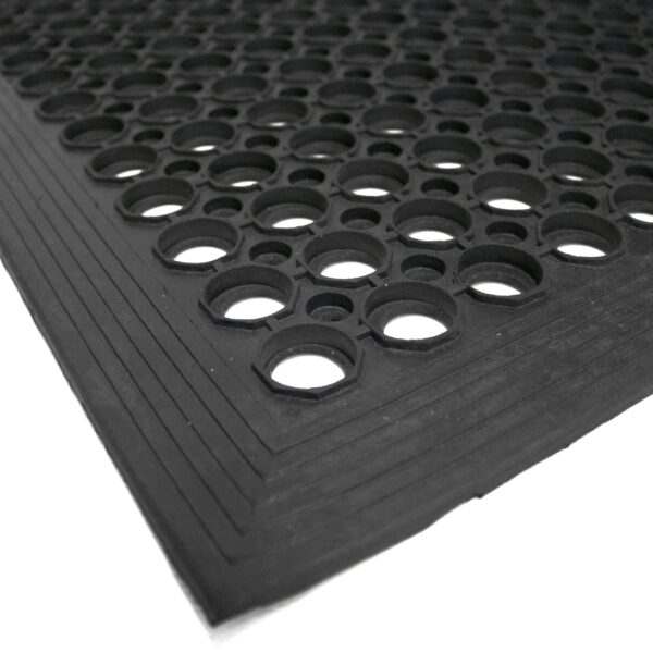 A close-up of the Large Front Door Mat Bundle shows its black rubber surface with circular holes and a textured, angled edge against a white background.