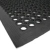 A close-up of the Large Front Door Mat Bundle shows its black rubber material with large round holes and a textured, bevelled edge, displayed on a white surface.