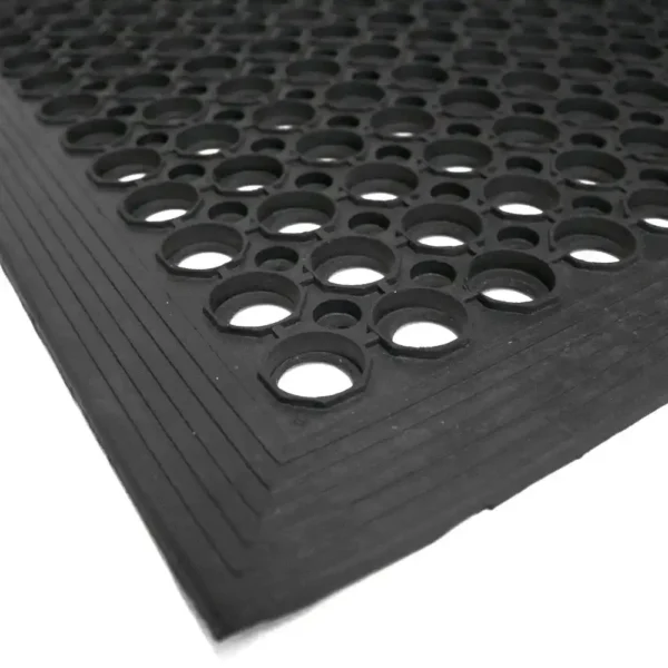 A close-up of the Large Front Door Mat Bundle shows its black rubber material with large round holes and a textured, bevelled edge, displayed on a white surface.
